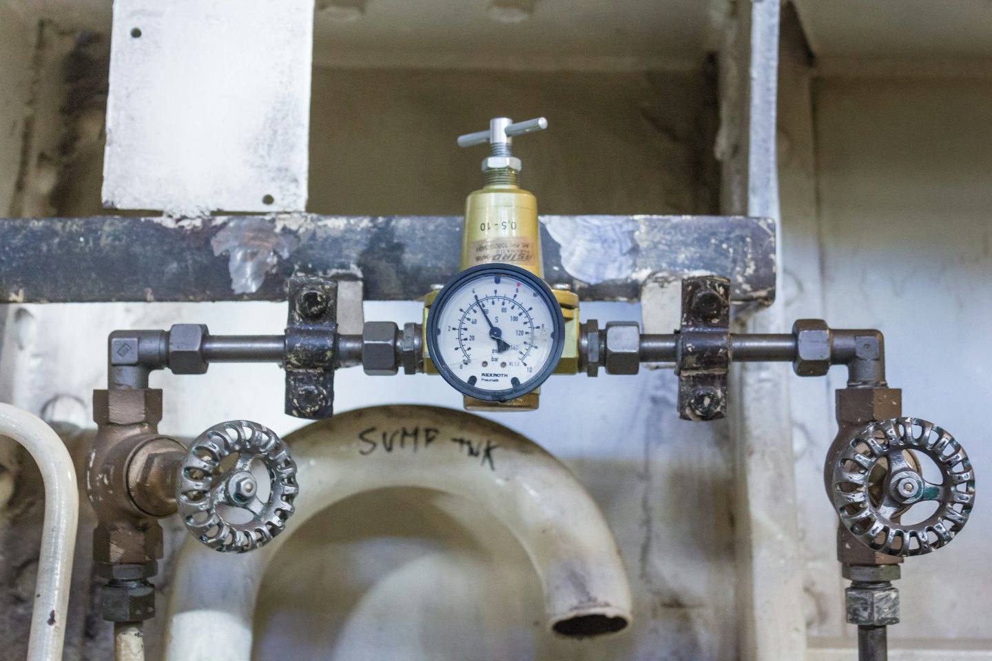 Industrial piping system featuring a central pressure gauge and valves.